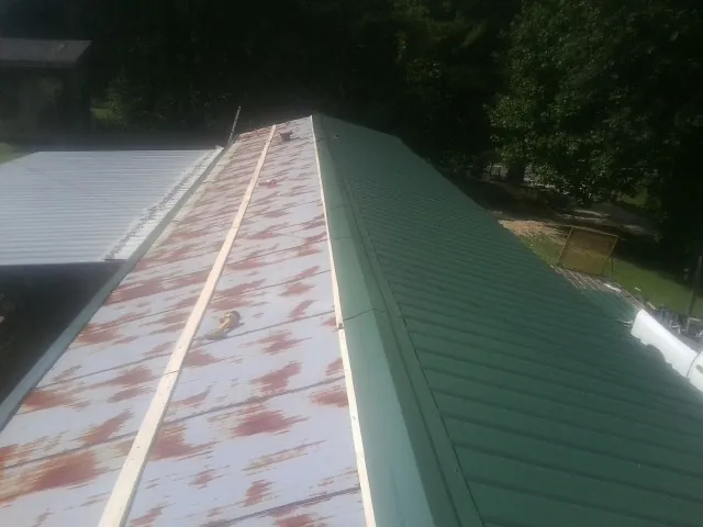 Old rusted panels beside newly installed green metal roofing — Wind Damage Roof Repair by Roofing Brothers in Prospect
