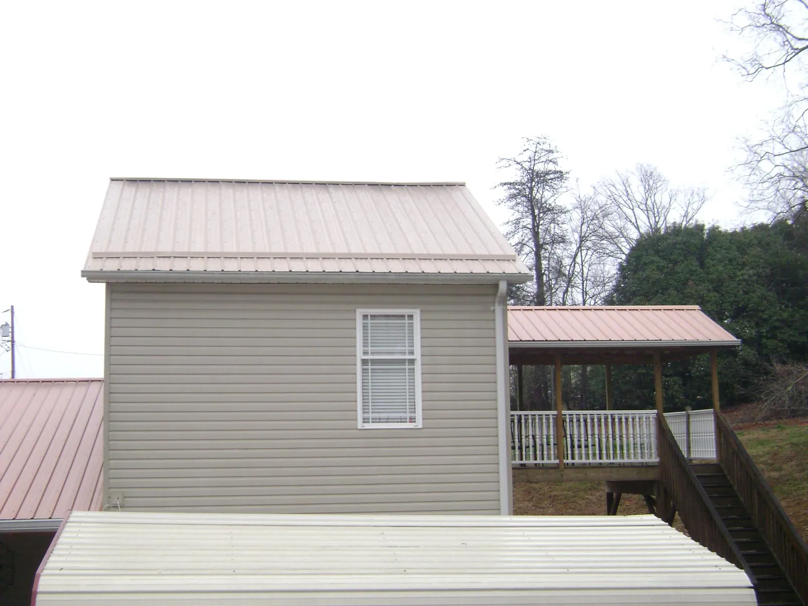 Tan metal roofs on a two story addition and attached porch, from a Roof Replacement job in Prospect